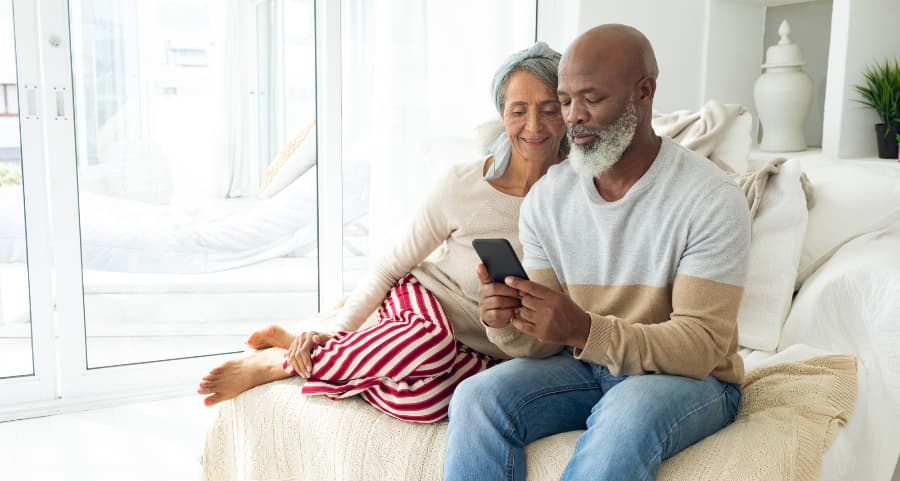 Senior couple relaxing on a couch and viewing a smartphone