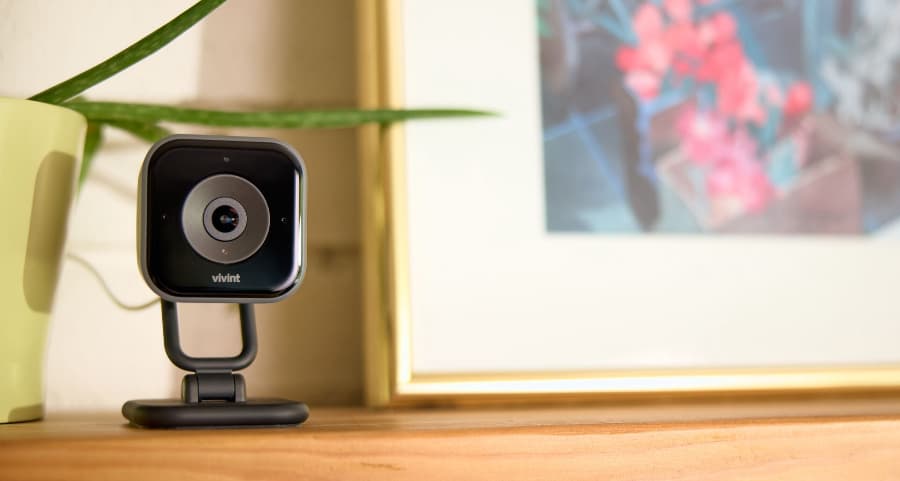 Vivint indoor camera placed on a mantel near a framed picture